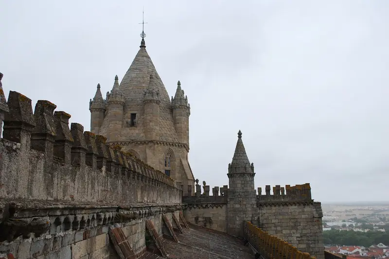On the roof of Évora Cathedral: a crenellated parapet leading to the cathedral's stone lantern tower.