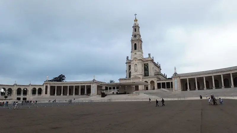 The Basilica of Our Lady of the Rosary at the Sanctuary of Fátima, with its tall tower and curved colonnades around the square.