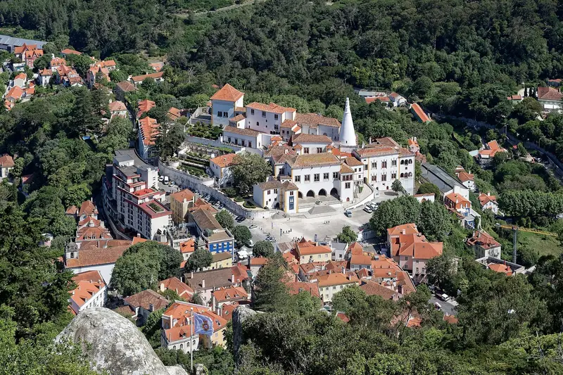 Sintra's historic centre seen from above, with the National Palace and its two white conical chimneys among the trees.