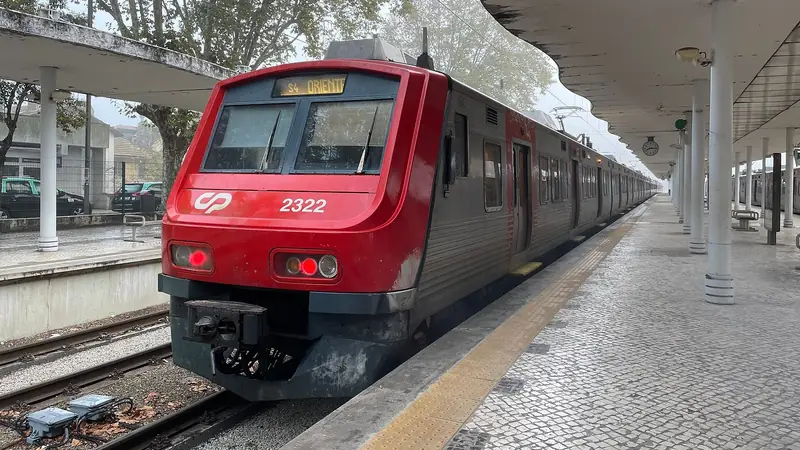 A red CP commuter train at a platform of Sintra station on a misty day.